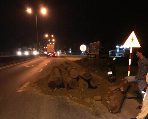 Số gỗ trên xe tải ben đỗ xuống mặt đường quốc lộ 1A trên.