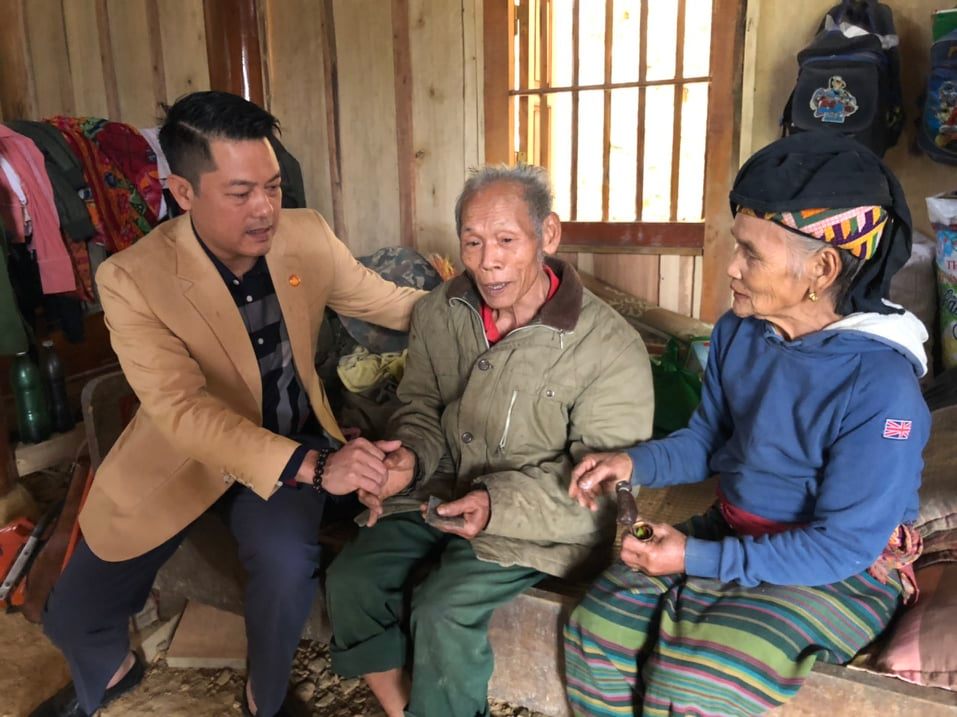 Anh Lê Văn Thành, Phóng viên Tạp chí Kinh tế Nông thôn thay mặt đoàn tặng quà và chúc Tết cụ Lô Tấn Đào huy hiệu 65 năm tuổi Đảng tại bản Xốp Cháo.